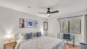 A bedroom with a bed, a desk, a chair, a ceiling fan, and framed pictures on the wall. - Newly Renovated Condo - Deck, Pet-Friendly, WFH (Austin)