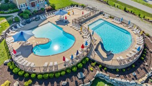 A large outdoor swimming pool with multiple sections, surrounded by lounge chairs and umbrellas.
