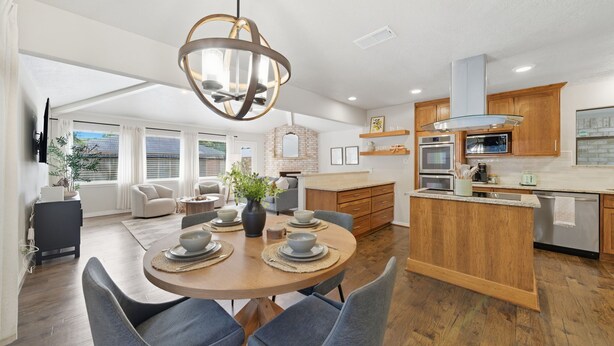 A modern kitchen with wooden cabinets, a central island, and built-in appliances.