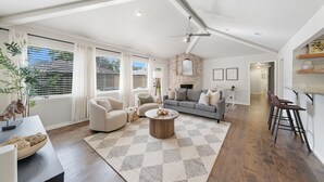 A spacious living area with a large window, a fireplace, and a dining area with bar stools.