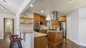 A modern kitchen with wooden cabinets, stainless steel appliances, and a central island with bar stools.