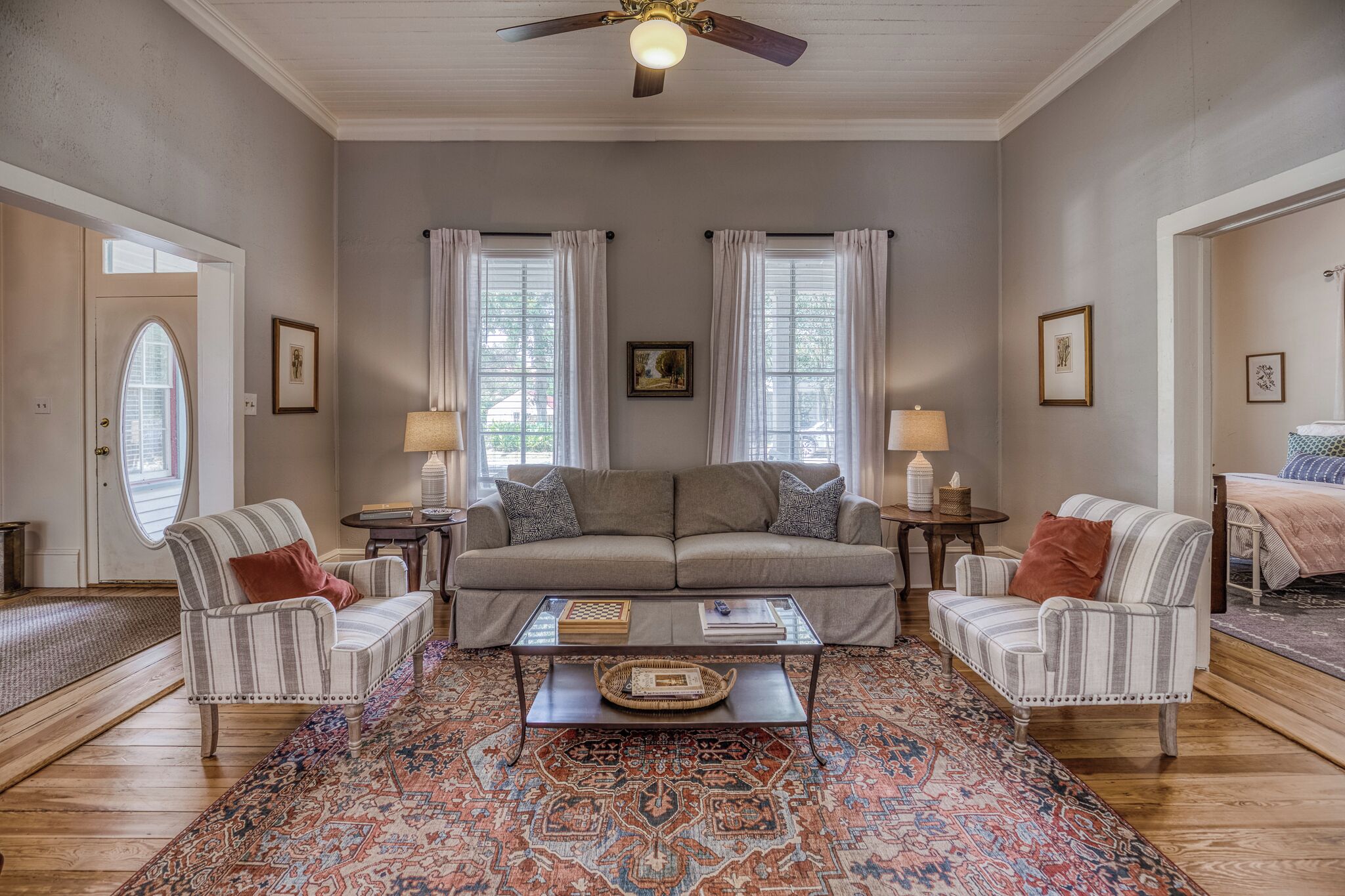 A living room with a sofa, two armchairs, a coffee table, and a patterned rug.