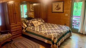 Dormitorio de cabaña de madera con cama, cómoda y vista al exterior.