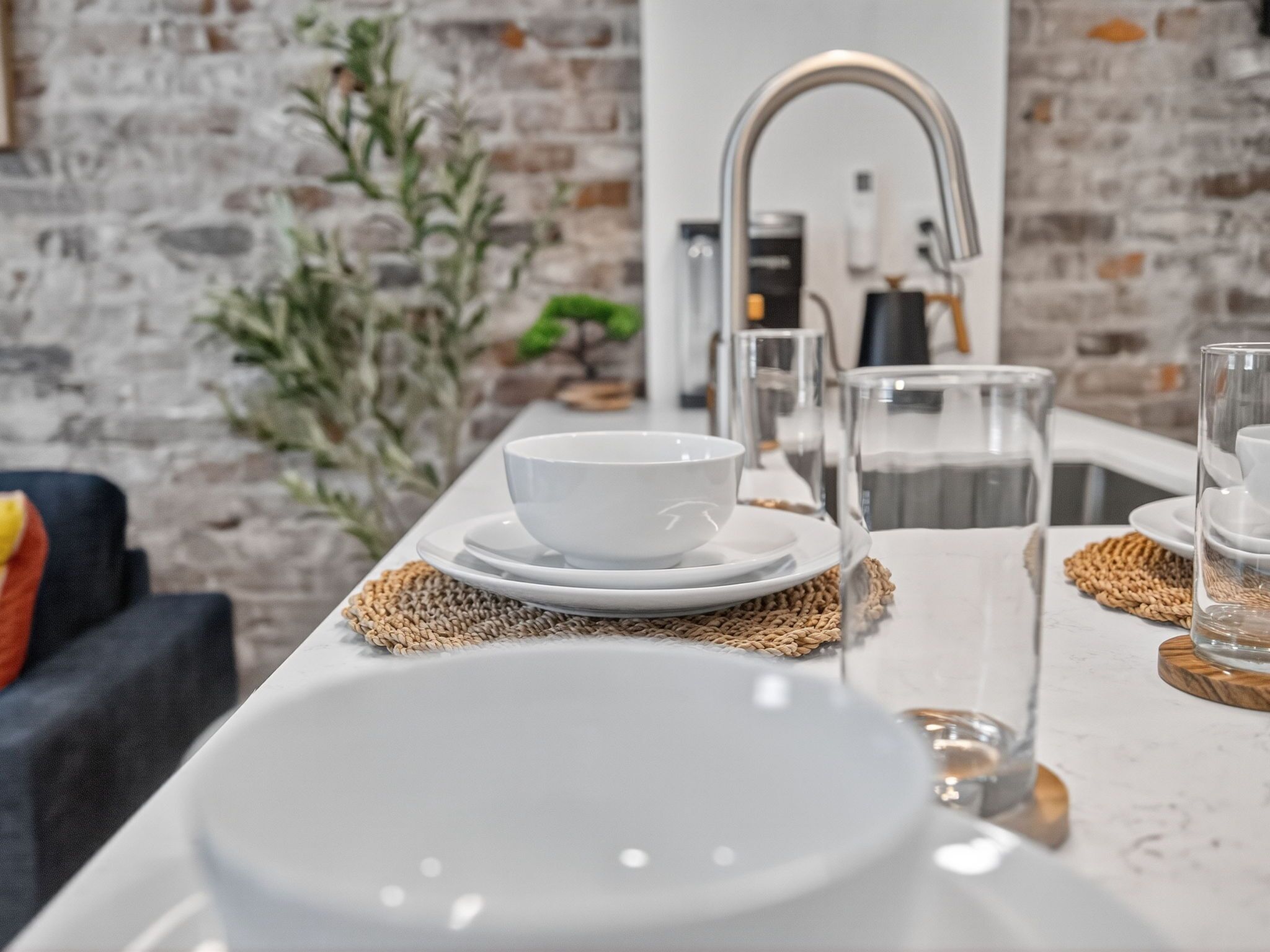 A modern kitchen with a white countertop, a sink, and a coffee machine.