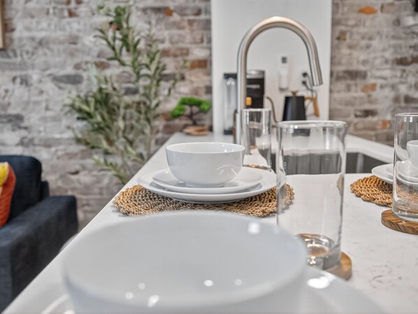 A modern kitchen with a white countertop, a sink, and a coffee machine.