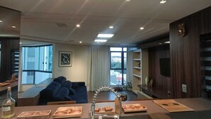 Et moderne køkken med en central ø, indbygget ovn og et stort vindue.