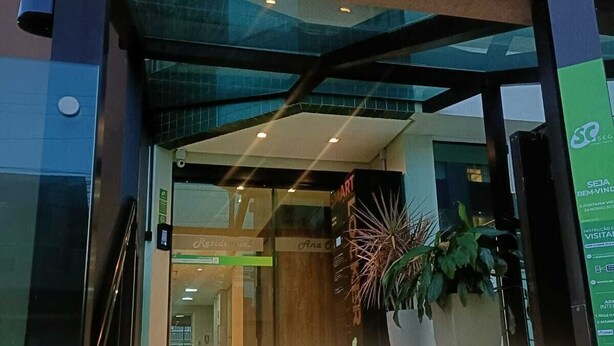 En moderne bygningsefterdør med en glasfacade, en trappe der fører op, og en stor plantekasse.