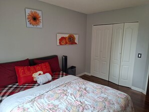 Een slaapkamer met een bed, een radiator, een kledingkast en twee aan de muur bevestigde foto's.