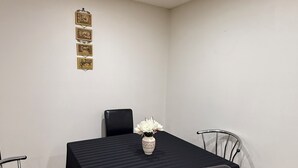 A dining area with a table covered by a black tablecloth, surrounded by four chairs, one of which is covered with a black cloth. A vase with white flowers is placed on the table. - Restful Pause on your Journey-14 mins to Airport, 3 beds, 1.5bath up to 6 guests (Calgary)