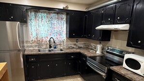 A kitchen with dark cabinets, a stainless steel refrigerator, a sink, a stove, and a microwave. - Restful Pause on your Journey-14 mins to Airport, 3 beds, 1.5bath up to 6 guests (Calgary)