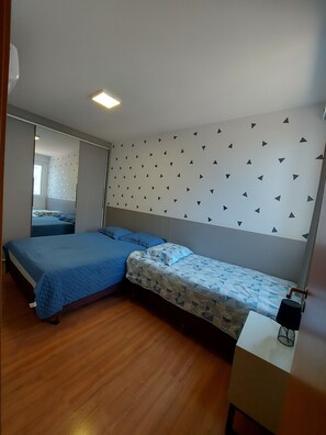 A bedroom with two beds, a wooden floor, a ceiling light, and a wall with a geometric pattern. - Apart. Standing on the sand in Barra Velha, 25 km from Beto Carrero (Barra Velha)