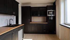 A modern kitchen with dark cabinetry, a wooden countertop, and a built-in oven.