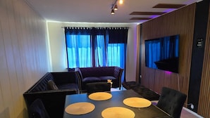 A dining area with a dark wooden table, four chairs, and a sofa.