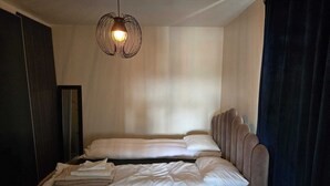 A hotel room with a bed, a hanging light fixture, and a window with curtains.