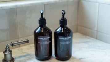 Two dark bottles labeled 'Grown Alchemist' on a bathroom countertop next to a sink.