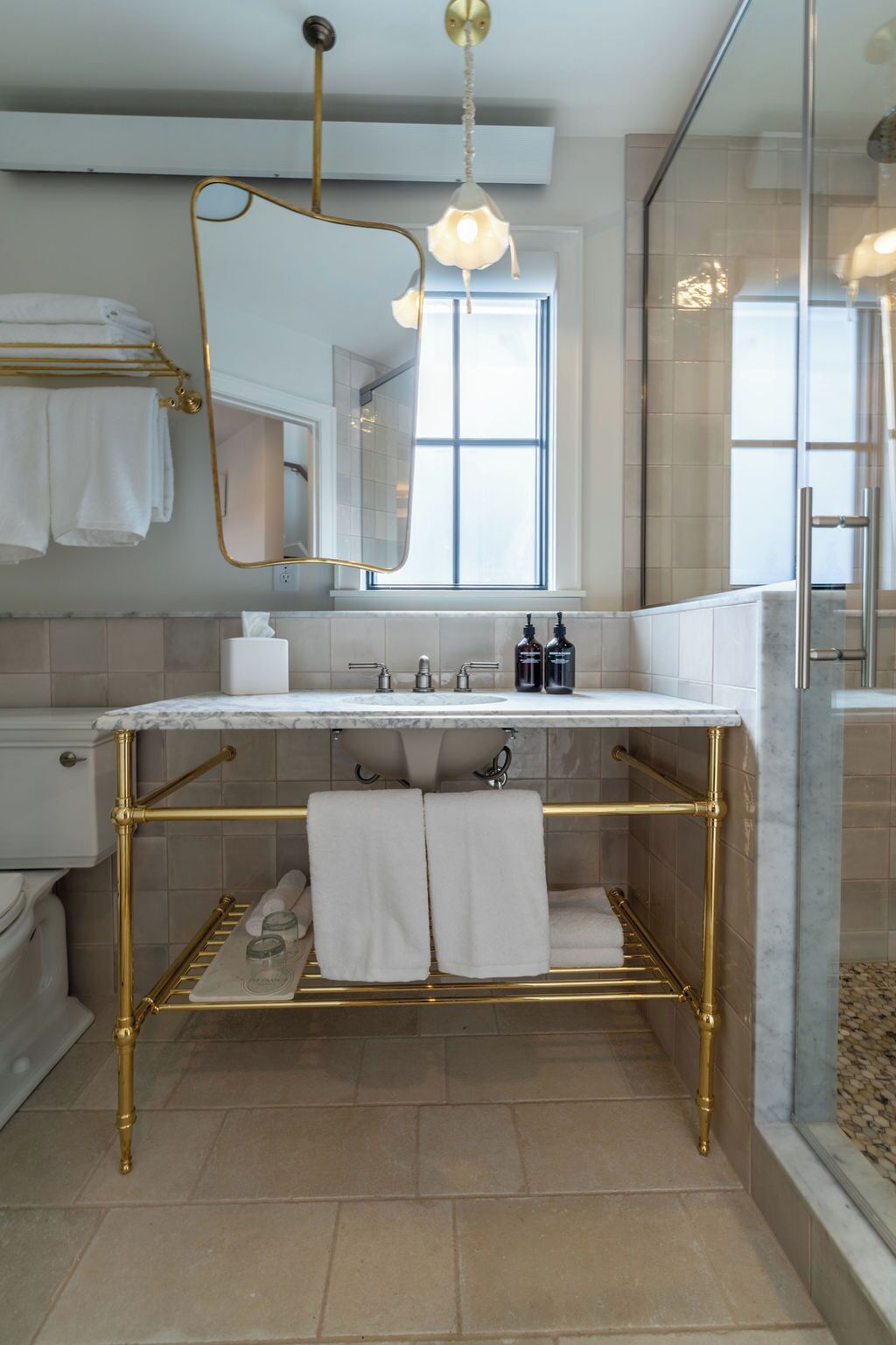 A modern bathroom with a gold vanity, white marble countertop, and a large mirror.
