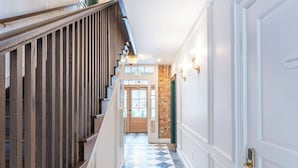 A hallway with a checkered floor, wooden railing, and a door with a keypad lock. - The Francis Hotel & Suites (Kennett Square)