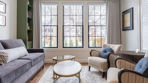 A living room with a grey sofa, striped armchairs, a round coffee table, and a patterned rug. - The Francis Hotel & Suites (Kennett Square)