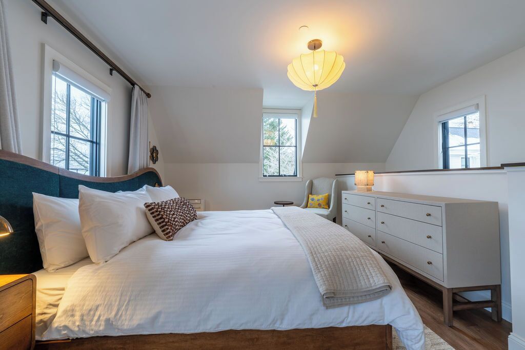 Une chambre à coucher avec un grand lit, des tables de chevet, une commode et un luminaire au plafond.