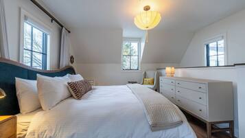 Une chambre à coucher avec un grand lit, des tables de chevet, une commode et un luminaire au plafond.