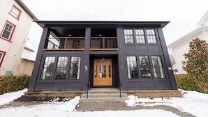 A two-story building with a dark facade, a wooden front door, and a balcony on the upper floor. - The Francis Hotel & Suites (Kennett Square)