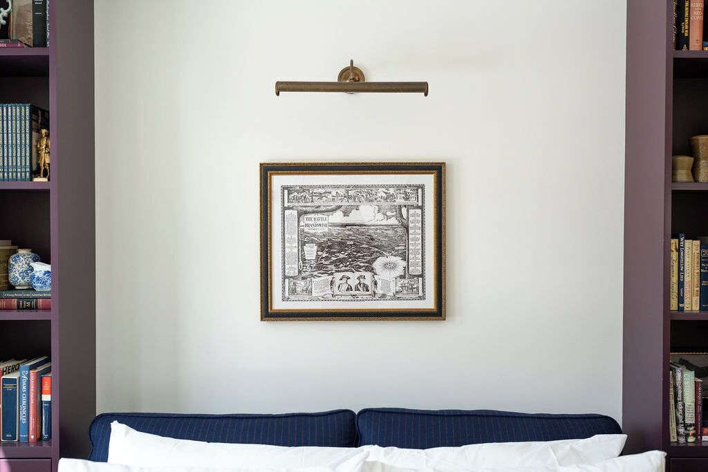 Una stanza con un letto, un quadro appeso al muro e librerie su entrambi i lati.
