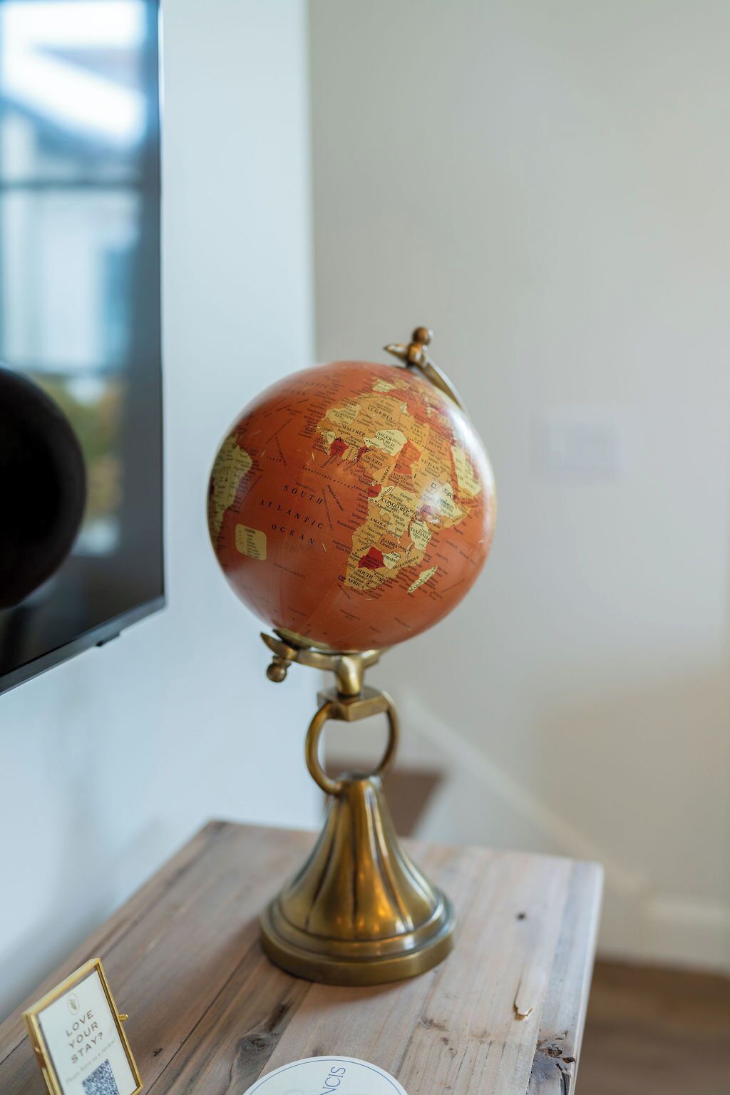 Een wereldbol op een houten standaard met een messing voet, geplaatst op een tafel.