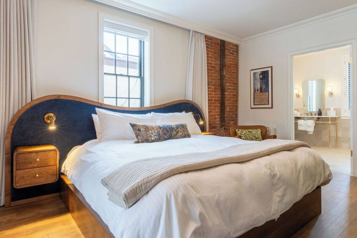 A spacious bedroom with a large bed, wooden headboard, and a modern chandelier.