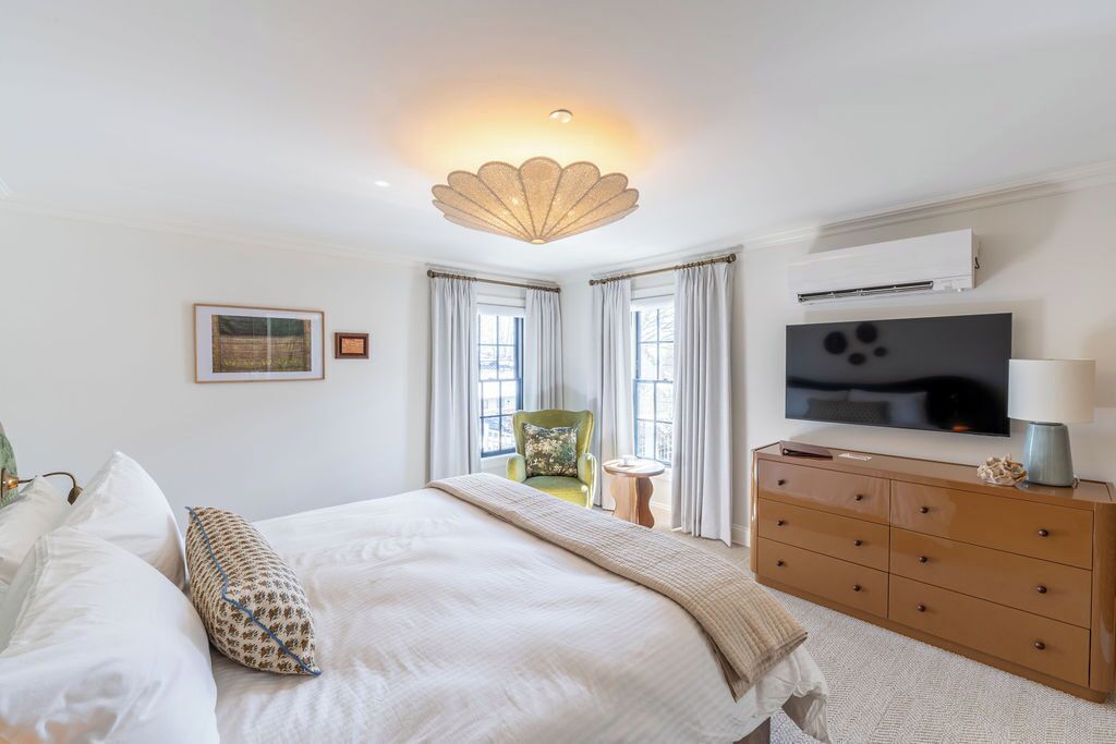 Une chambre à coucher avec un lit, une commode, un téléviseur et une chaise.