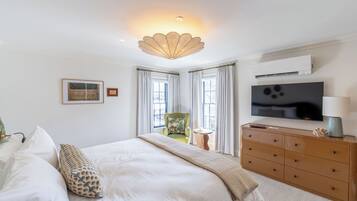Une chambre à coucher avec un lit, une commode, un téléviseur et une chaise.