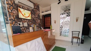 A reception desk with a patterned wall, a framed picture, and a laptop. - Shri Radha hotels (Ujjain)