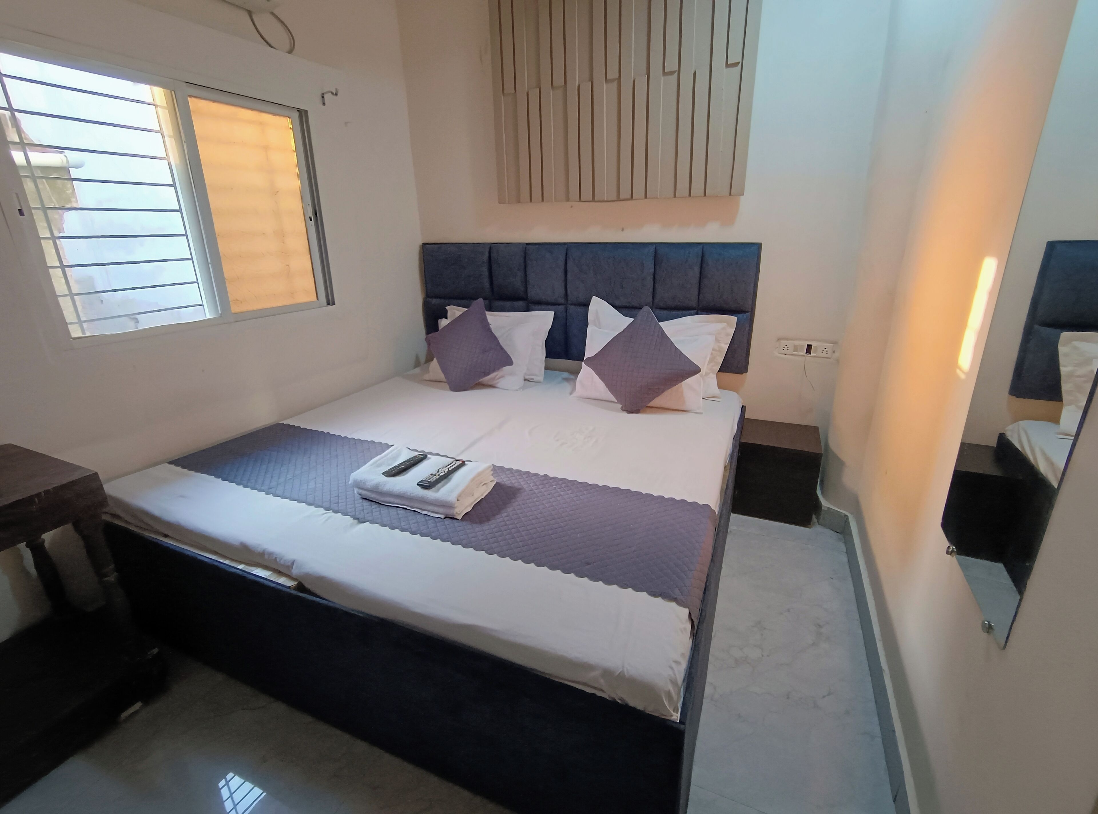 A neatly arranged bedroom with a bed, bedside tables, and a window with blinds.