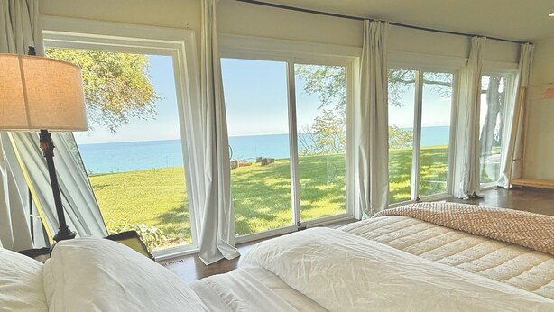 Un dormitorio con dos camas, ventanas amplias y vista al mar.