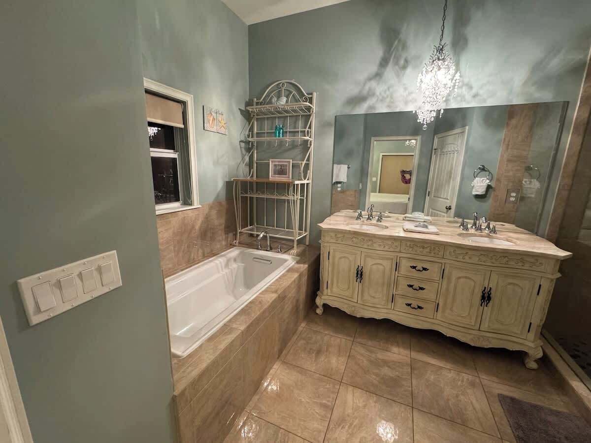 Un baño con bañera, tocador con doble lavabo y un espejo grande.