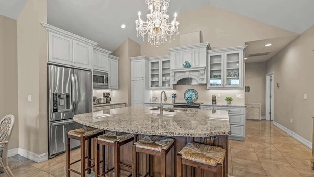 A spacious kitchen with a large island, stainless steel appliances, and a chandelier.