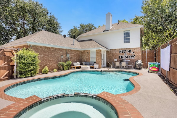 Un jardin avec une piscine, un patio couvert et un panneau sur lequel on peut lire : « DONNEZ-MOI RENDEZ-VOUS À FRISCO, au Texas ».