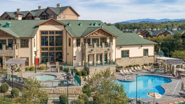 Ein Resort mit großem Pool, Steinfassade und mehreren Balkonen.