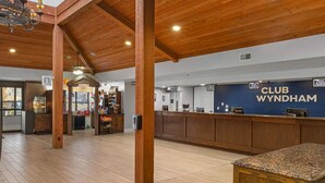 Eine großzügige Lobby mit Holzbalken und einer Rezeption mit der Aufschrift "CLUB WYNDHAM".