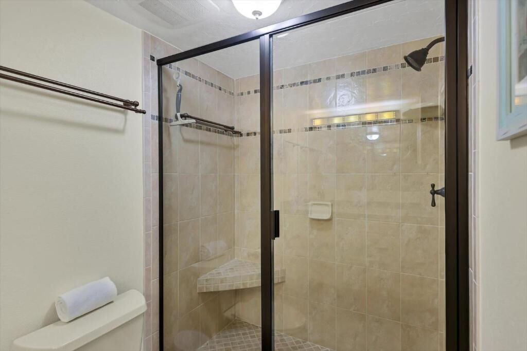 A glass-enclosed shower with a towel rack and a small shelf.