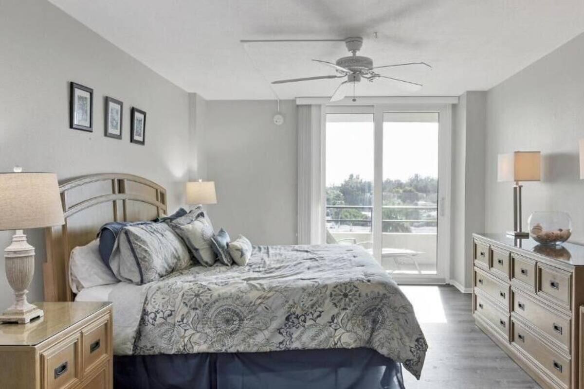 A bedroom with a bed, bedside tables, a dresser, and a ceiling fan.