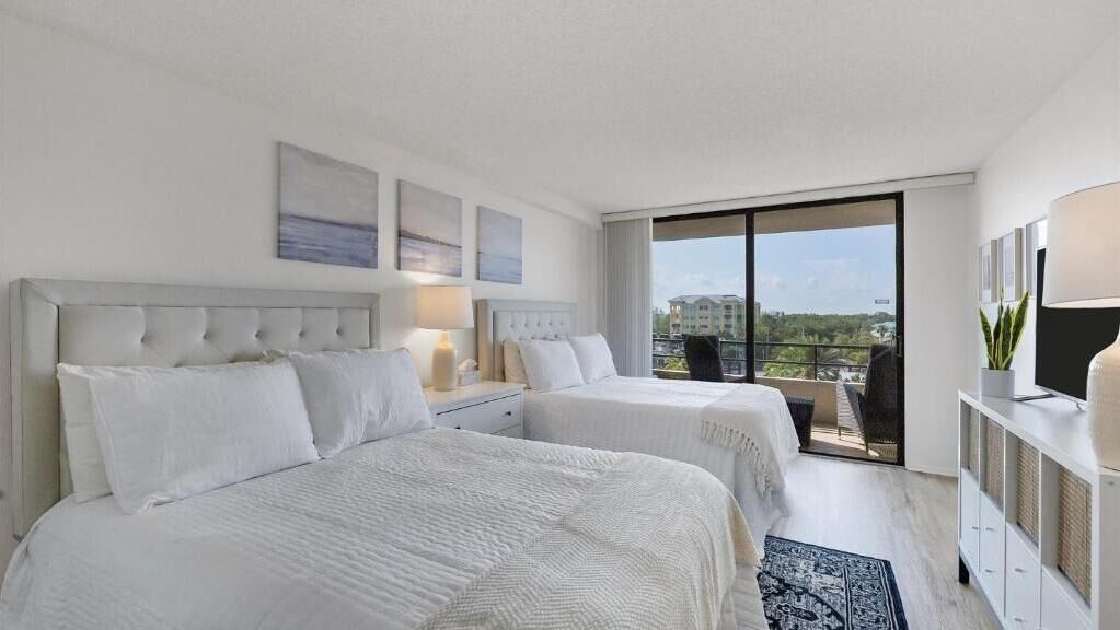Een hotelkamer met twee bedden, een balkon met uitzicht en een televisie op een kast.