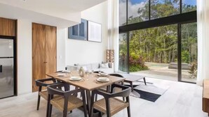 A modern kitchen with a dining area, large windows, and a view of greenery. - Luxury Boho Villa w/ Pool, 5 Min to Tulum Beach (Tulum)