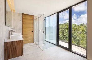 A modern bathroom with a large window, a wooden door, and a white sink.
