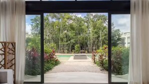 A modern room with a large sliding glass door leading to a pool and garden. - Luxury Boho Villa w/ Pool, 5 Min to Tulum Beach (Tulum)