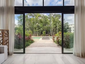 A modern room with a large sliding glass door leading to a pool and garden.