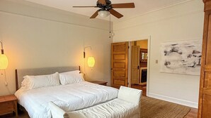 A bedroom with a large bed, a bench, a wooden floor, and a ceiling fan. - Newly Updated Historic Baton Rouge Home, Near LSU & Downtown--3 BR/Sleeps 6 (Baton Rouge)