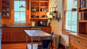 A kitchen with wooden cabinets, a dining table, chairs, a microwave, and a window with blinds. - Newly Updated Historic Baton Rouge Home, Near LSU & Downtown--3 BR/Sleeps 6 (Baton Rouge)