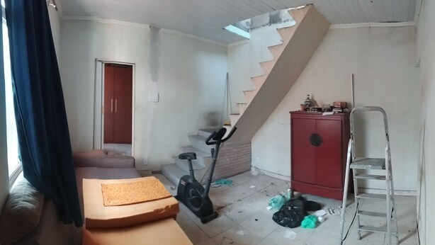 A room with a staircase, a red cabinet, a treadmill, and scattered items on the floor. - Village Apartment Building (Rio de Janeiro)