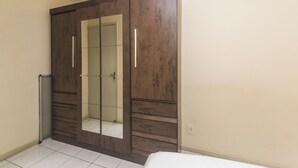 A bedroom with a large wardrobe, a bed, and a tiled floor. - Cozy Apartment near Cambirela CFT (Palhoça)