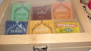 Una caja de madera que contiene seis bolsitas de té Pukka con distintos sabores.